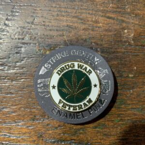 Enamel pin featuring marijuana leaf motif.