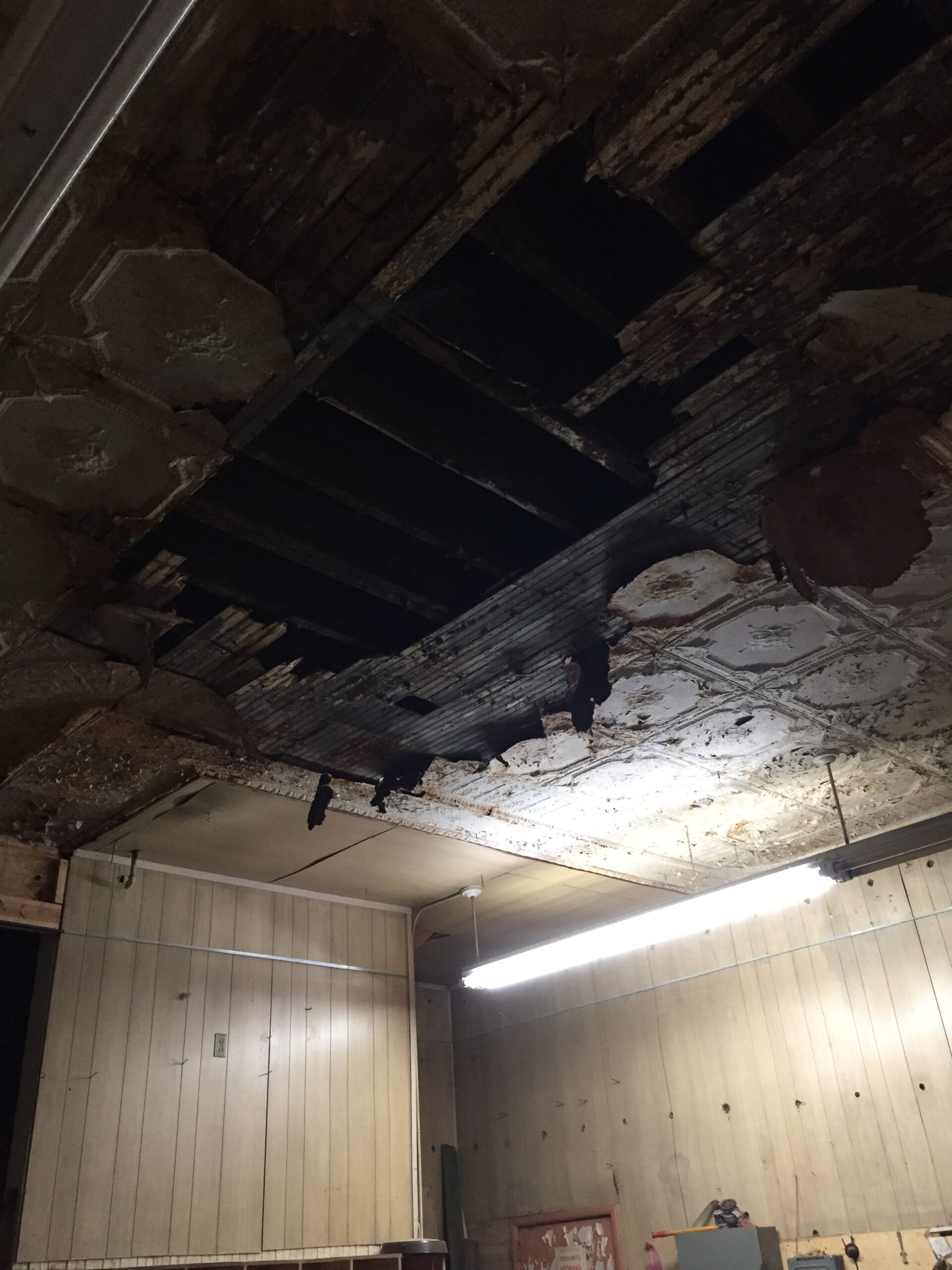 Ceiling tiles missing, revealing dark beams