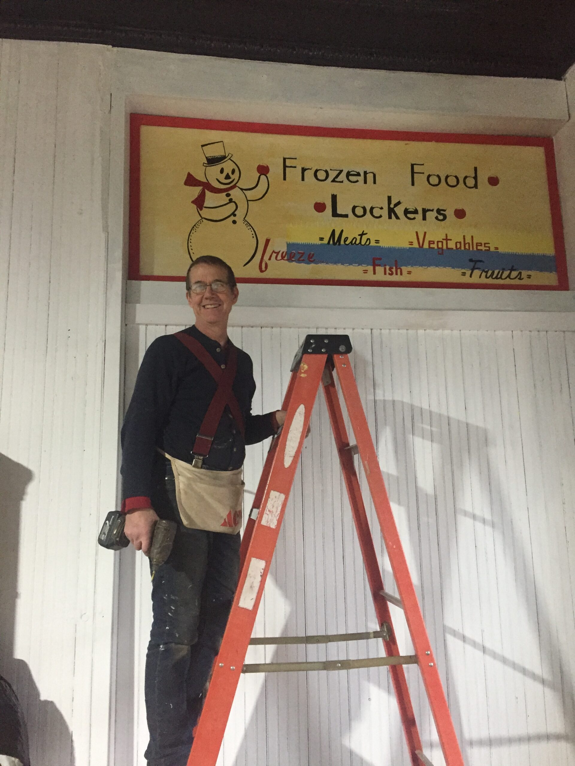 Artist restoring old food locker sign